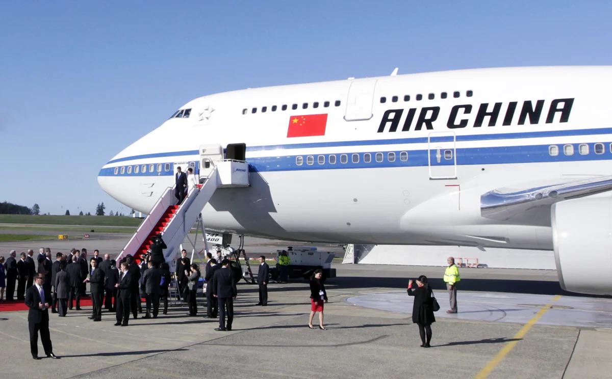 Air China Boeing 747 with passengers descending red-carpeted aircraft stairs at an airport
